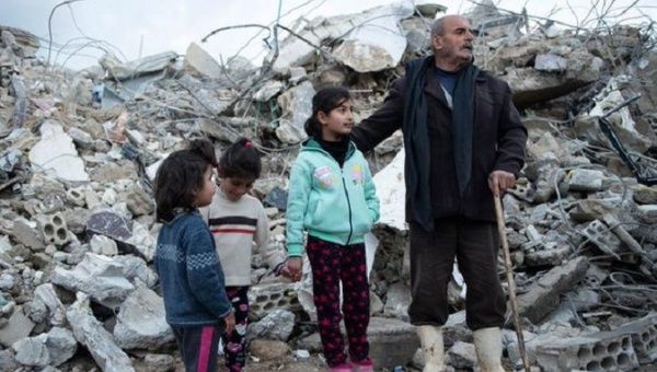 A family stands near the rubble of their home, Syria, Feb. 10, 2023.
