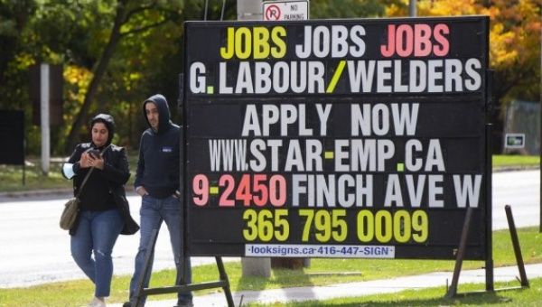 People walk past a job board by a street in Toronto, Canada, on Oct. 7, 2022.
