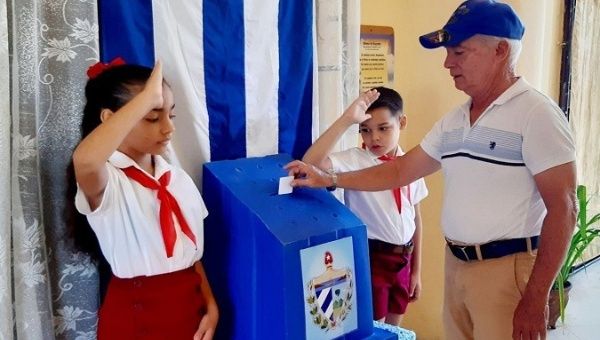 A citizen enters his ballot into a voting booth, Cuba. 