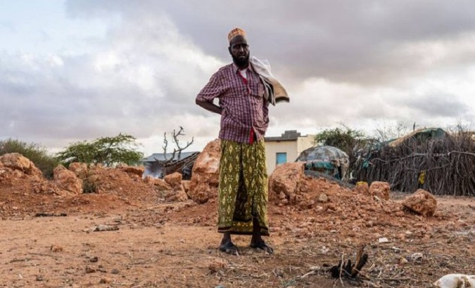 An African farmer stands on arid ground.