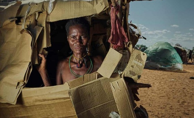 Peter Caton's photograph of a woman in her cardboard shelter at Etunda camp, Namibia, 2022.