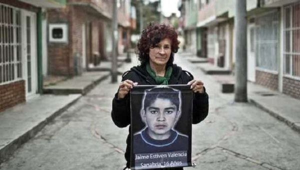 Colombian woman holds the photo of her missing son.