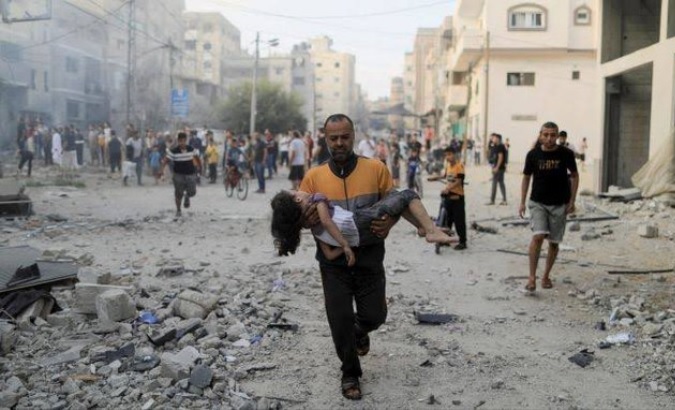 Man carries injured child in Gaza, Oct. 14, 2023.