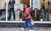 A woman walks past a store with discount signs in Brussels, Belgium, Oct. 31, 2023. 