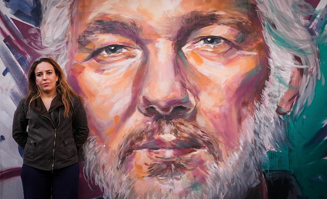 Stella Assange stands in front of a painting of her husband, Julian.