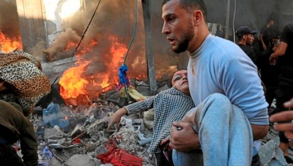 A Palestinian helps a child after an Israeli bombing in Gaza, Dec. 2023.