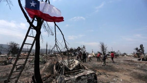 Chileans collect debris caused by a fire, Feb. 4, 2024.