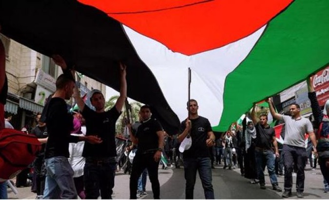 People hold a giant Palestinian flag, 2024.